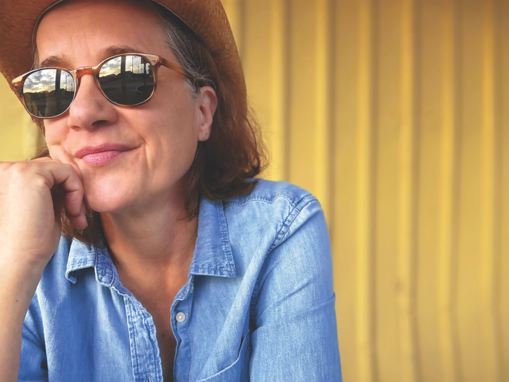 Susan Werner looking off into the distance wearing sunglasses and a blue shirt Promo Shot for Halfway to Houston in CMYK format